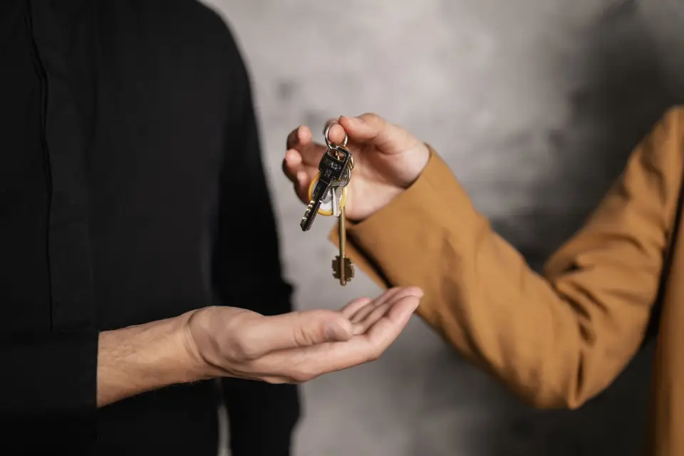 One person handing a set of house keys to another